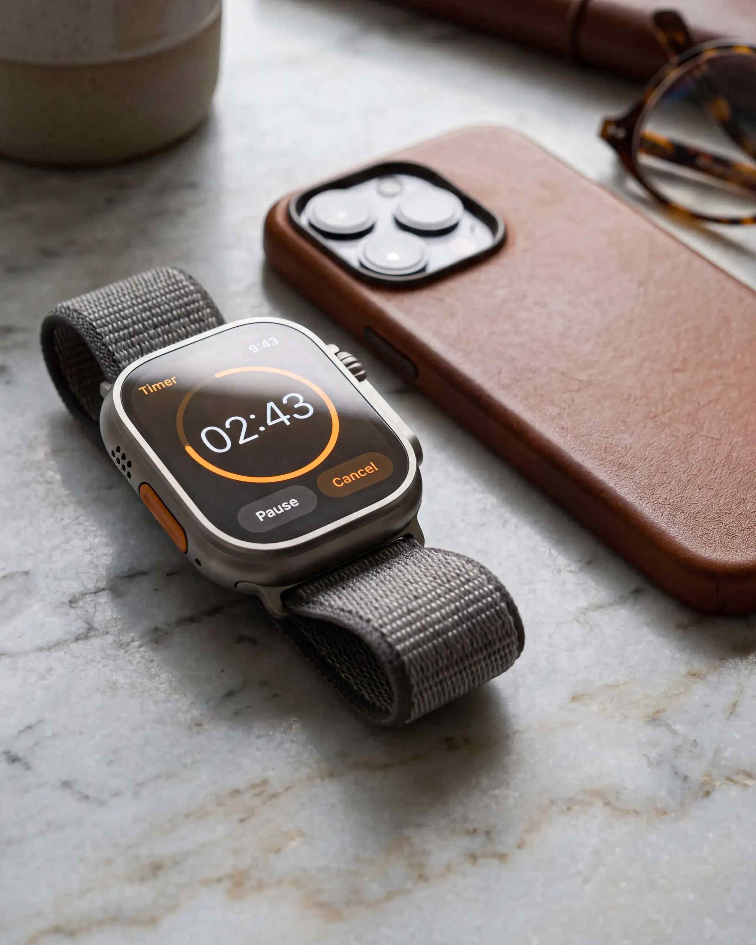 A smart watch and iPhone sitting next to each other on a desk.